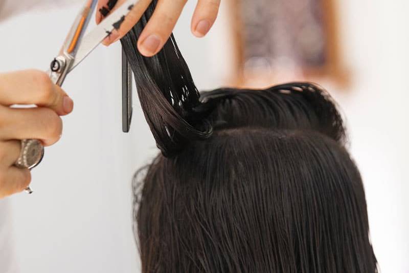Eine brünette Person von hinten, die einen neuen Haarschnitt erhält.