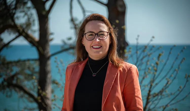 Dorothee Schicht on the beach in Binz with water and trees behind – Executive assistant at Rugard Thermal Strandhotel