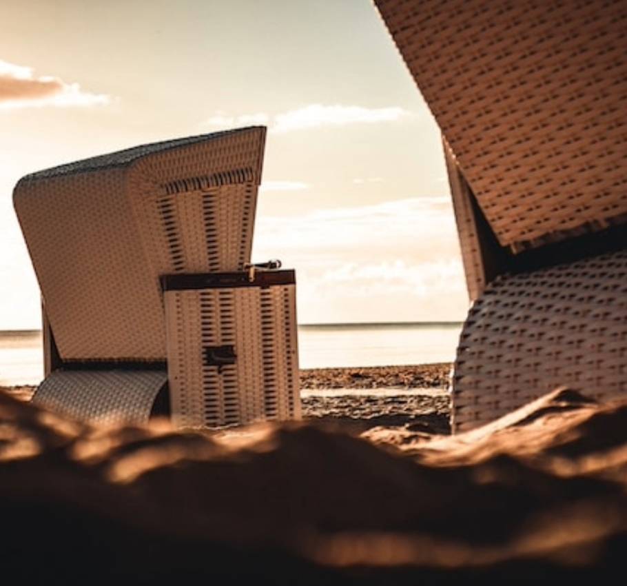 Detailaufnahme von Strandkörben am Strand bei Sonnenuntergang.
