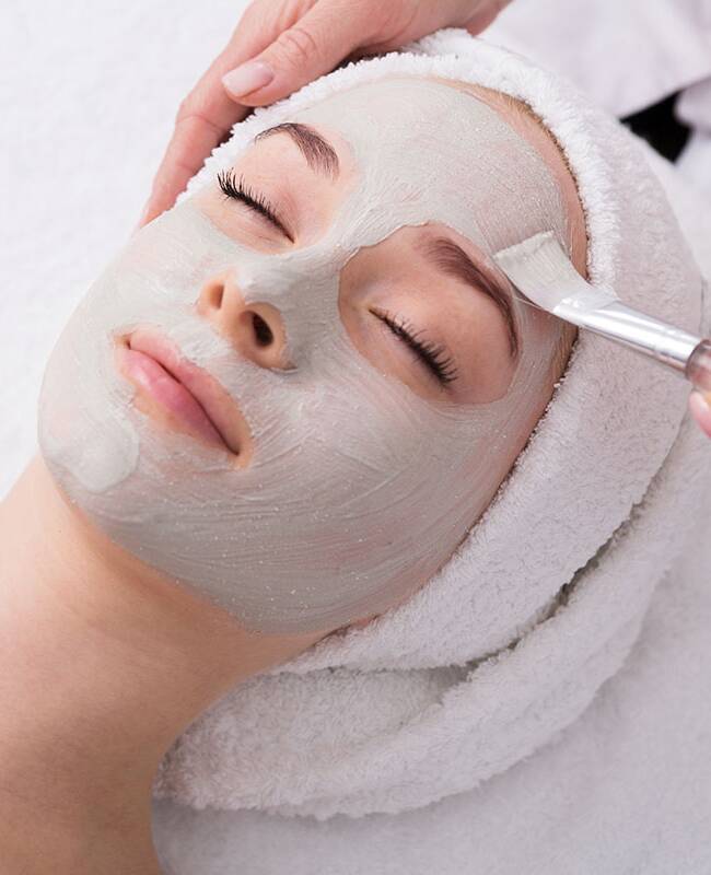 Eine Gesichtsmaske von Biodroga wird sanft bei einer Frau aufgetragen.