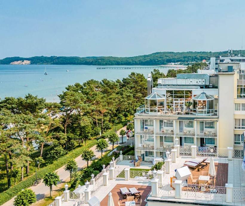 Luftaufnahme des Rugard Thermal Strandhotels, mit dem Meer, der Küste und einer Seebrücke im Hintergrund.