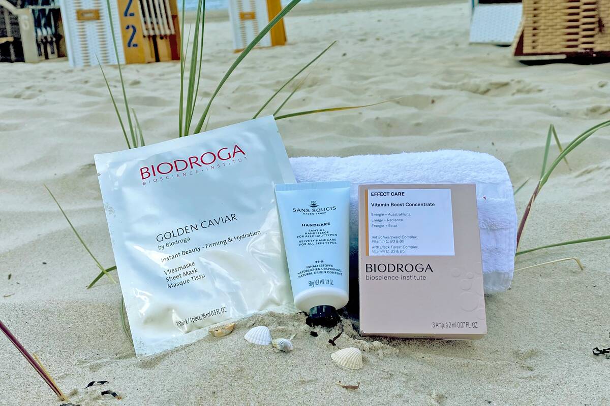 Kosmetikprodukte von Biodroga auf einem Handtuch im Sand.
