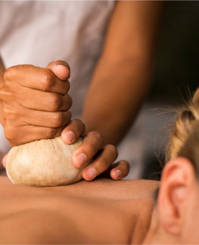 Eine Frau bekommt eine Kräuterstempel Massage.