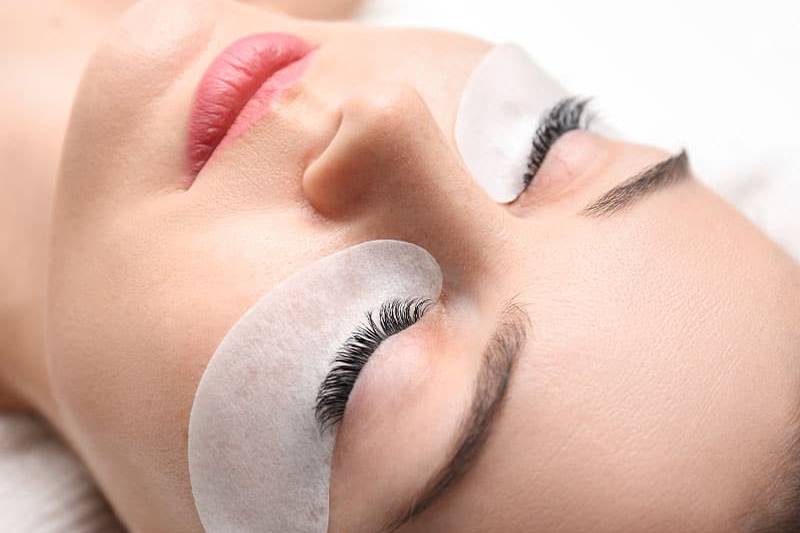 Eine Frau entspannt, während ihre Wimpernpflege auf Schutzpads einwirkt.