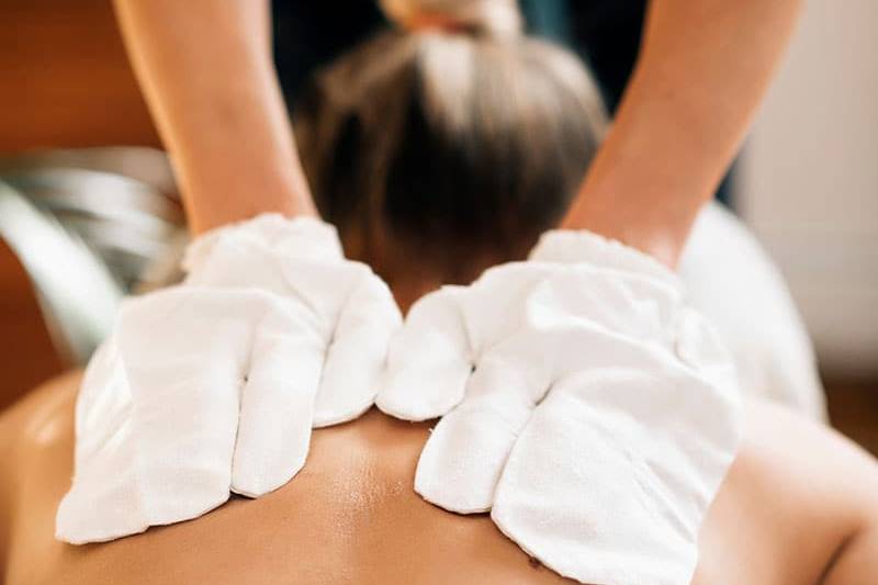 Eine Frau erhält eine Rückenmassage mit original ayurvedischen Seidenhandschuhen.