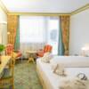 Hotelzimmer mit Stühlen, Tisch und weißem Doppelbett im Landhaus Stil