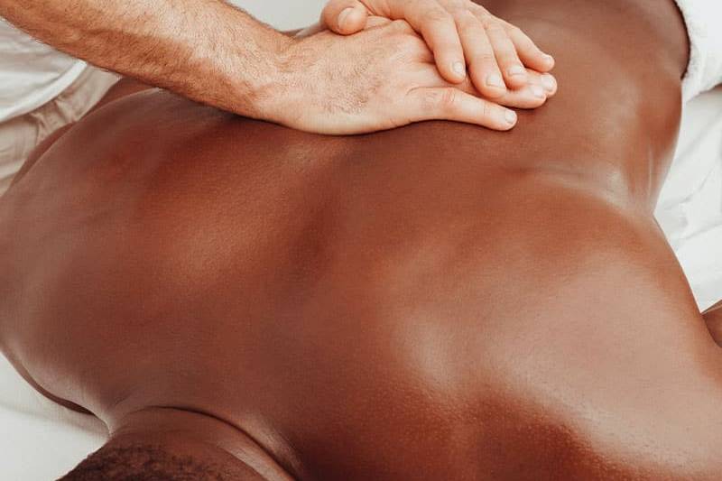Ein Mann entspannt bei kräftiger Massage der mittleren Rückenmuskulatur.