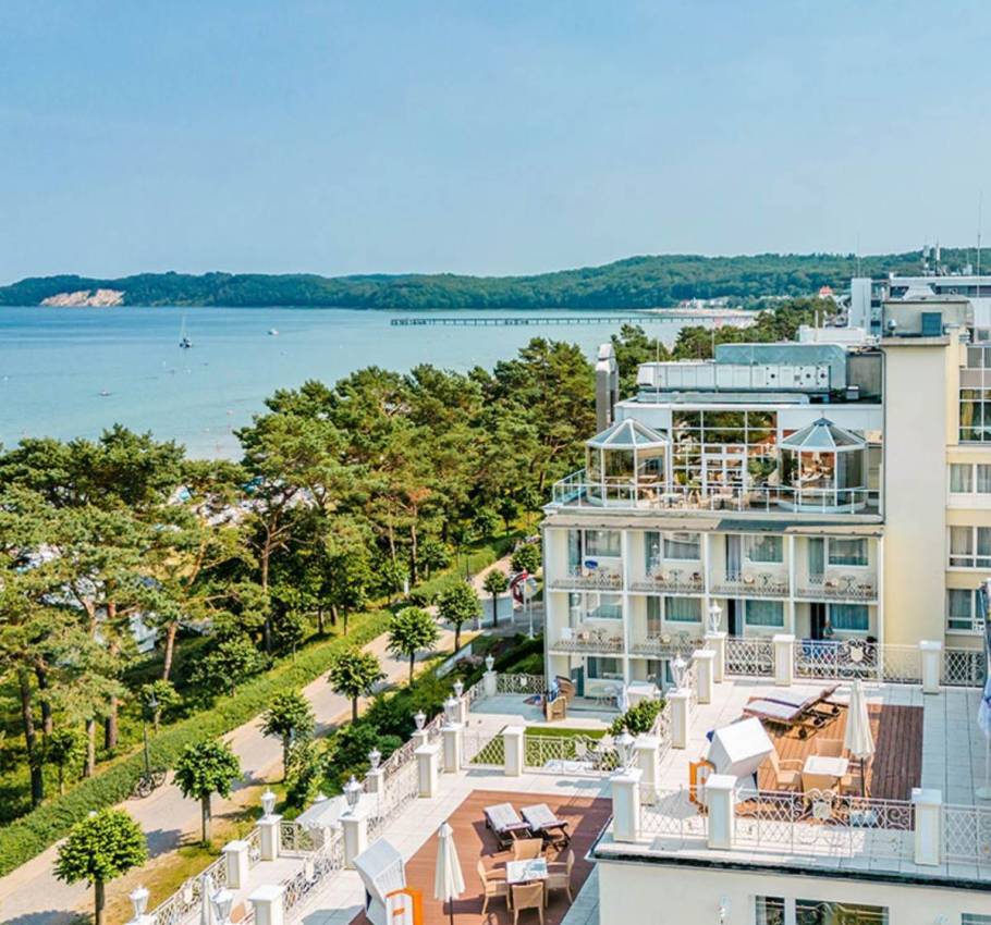 Luftaufnahme des Rugard Thermal Strandhotels, mit dem Meer, der Küste und einer Seebrücke im Hintergrund.