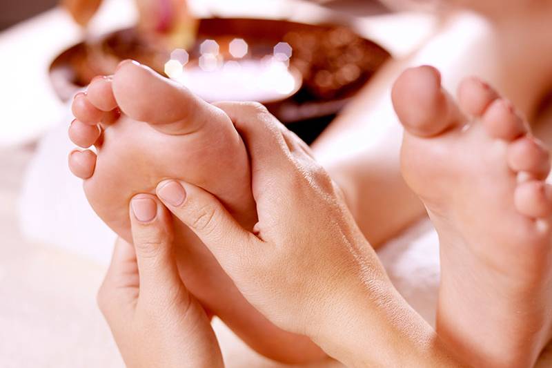 Eine sanfte Massage der Fußreflexzonen auf einer Massageliege.