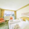 Hotelzimmer mit Stühlen, Tisch und weißem Doppelbett im Landhaus Stil