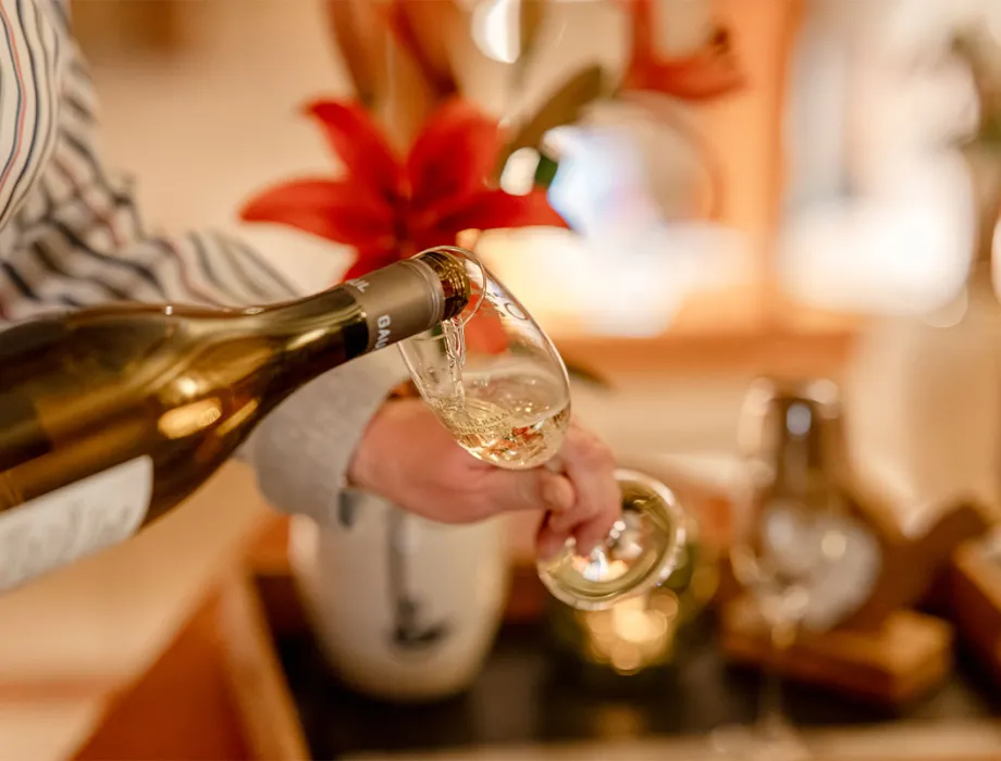 Champagne is poured into a glass, festive decorations in the background at a banquet in the Rugard Thermal Strandhotel.