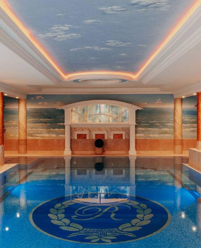 Ein blauer Pool mit dem Hotellogo am Grund, an den Wänden sind Malereien der Natur im Wellnessurlaub auf Rügen.