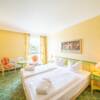 Gemütliches Hotelzimmer mit Doppelbett, in der Ecke ein Sessel und ein Bild an der Wand.