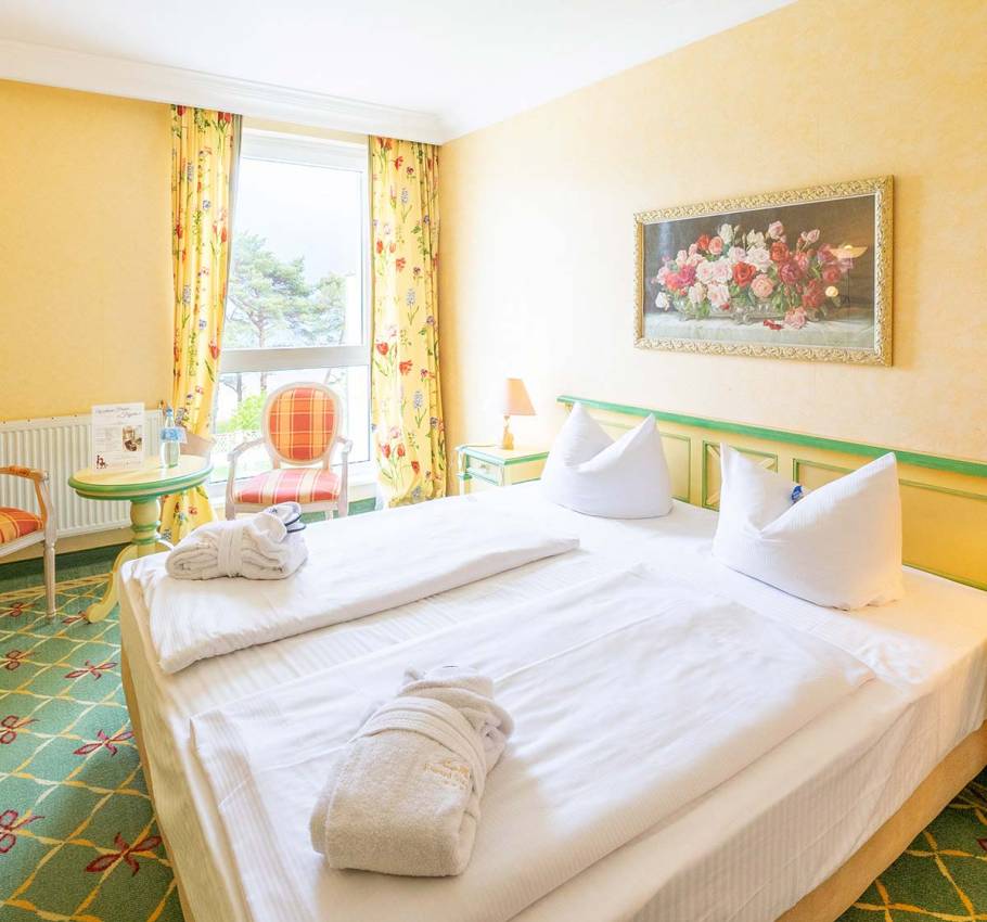 Doppelzimmer im Rugard Strandhotel Binz mit großem Bett, stilvollen Möbeln und Balkon mit Meerblick.