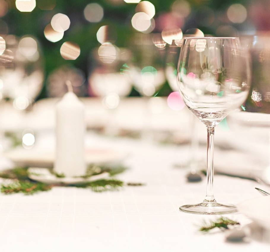 An empty glass is placed on a white table with an Advent decoration and a white candle.