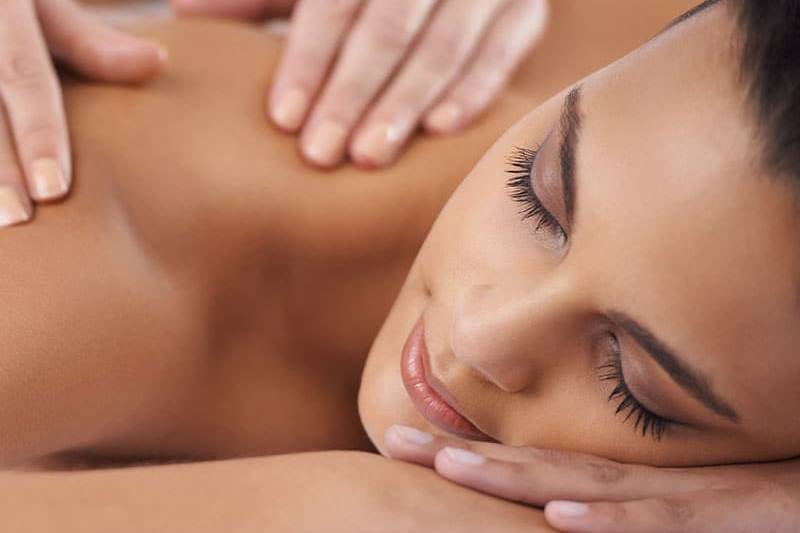 Eine Frau genießt ihre Massage im Schulter-Nacken-Bereich.