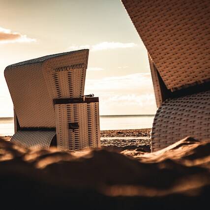 Detailaufnahme von Strandkörben beim Sonnenuntergang am Strand.
