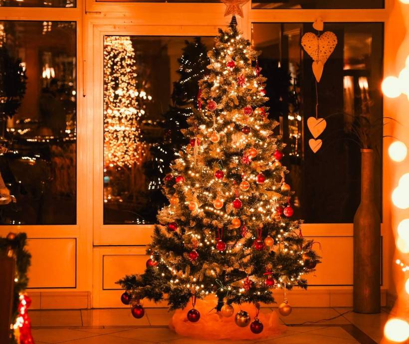 Festlich beleuchteter Weihnachtsbaum in einem gemütlich dekorierten Hotelbereich während der Weihnachtszeit.