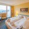Zur Ausstattung der Doppelzimmer mit Stadtblick und Balkon im Rugard Thermal Strandhotel gehören Sitzmöbel sowie Schreibtisch mit Schreibmappe.