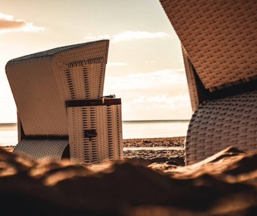 Detailaufnahme von Strandkörben am Strand bei Sonnenuntergang.