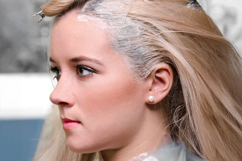 Eine blonde Frau erhält eine Auffrischung ihrer Blondierung am Haaransatz.