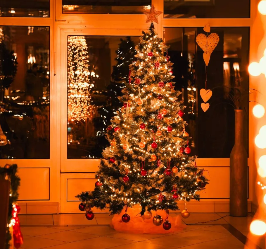 Festlich beleuchteter Weihnachtsbaum in einem gemütlich dekorierten Hotelbereich während der Weihnachtszeit.