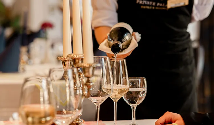 A waiter pours champagne into glasses at a festively laid banquet table in the restaurant of the Rugard Thermal Strandhotel.