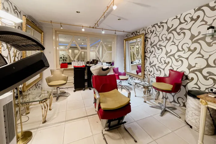 Exklusiver Friseursalon mit roten Sesseln und goldenen Akzenten im Wellness Hotel auf Rügen.