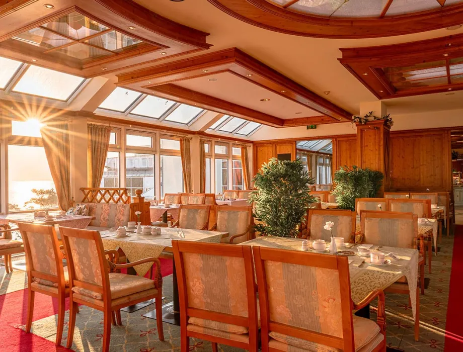 Dekorierte Vierertische in einem sonnendurchfluteten Restaurantraum in Binz mit Blick auf die Ostsee.
