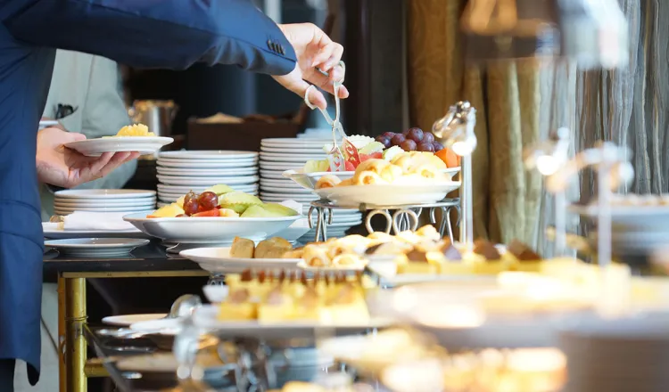 A guest helps himself to the generous breakfast buffet with fruit and pastries.