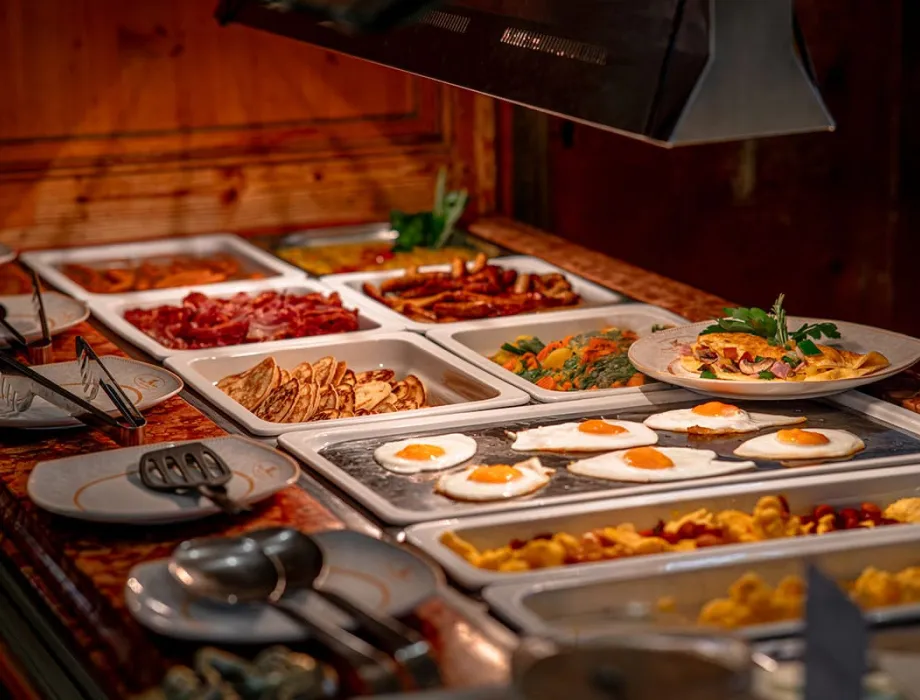 Ein abwechslungsreiches und frisches Frühstücksbuffet mit Spiegeleiern, Pfannkuchen und Speck im Hotelrestaurant in Binz.