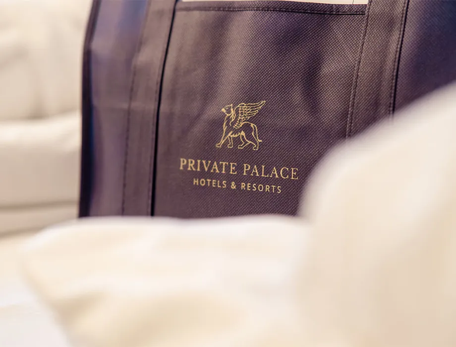 High-quality fabric bag with Private Palace Hotels & Resorts logo on the bed at Rugard Strandhotel Binz