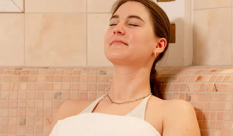 Woman leans back and relaxes with her eyes closed during a wellness session in the caldarium at the Rugard Thermal Strandhotel in Binz on the island of Rügen.