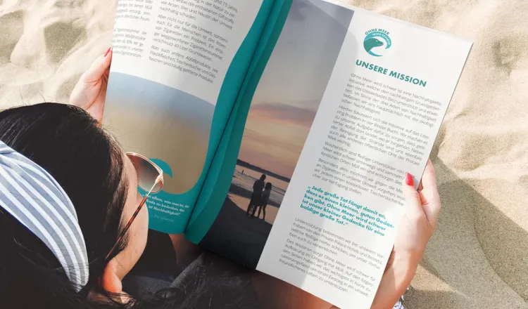 Woman with magazine on the beach of Binz – Rugard Thermal Strandhotel actively supports the "Ohne Meer wird schwer" campaign