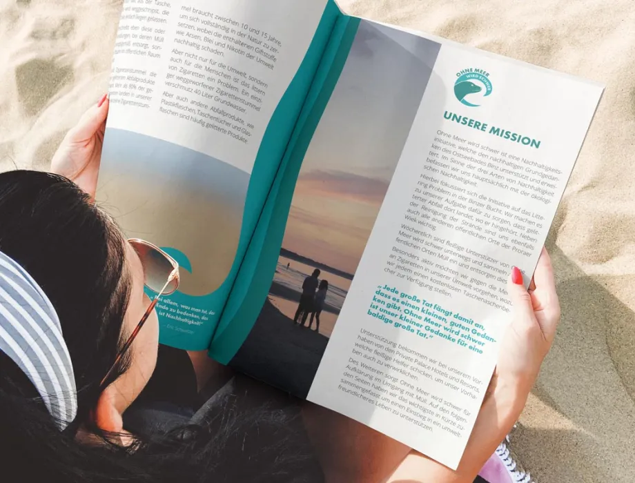 Frau mit Magazin am Strand von Binz – Rugard Thermal Strandhotel beteiligt sich aktiv an der Umweltkampagne „Ohne Meer wird schwer“