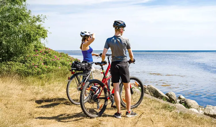 A couple admires the sea view during a cycling trip. Numerous rental options make spontaneous tours easy!