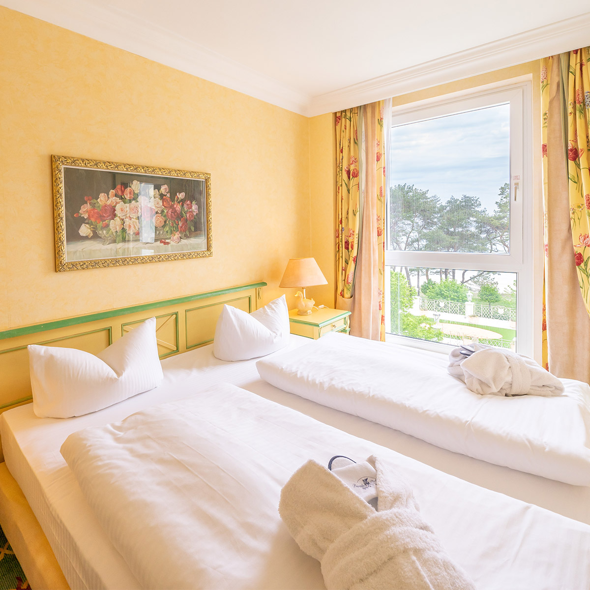 Ein gemütliches Hotelbett vor einem Fenster mit Blick aufs Meer