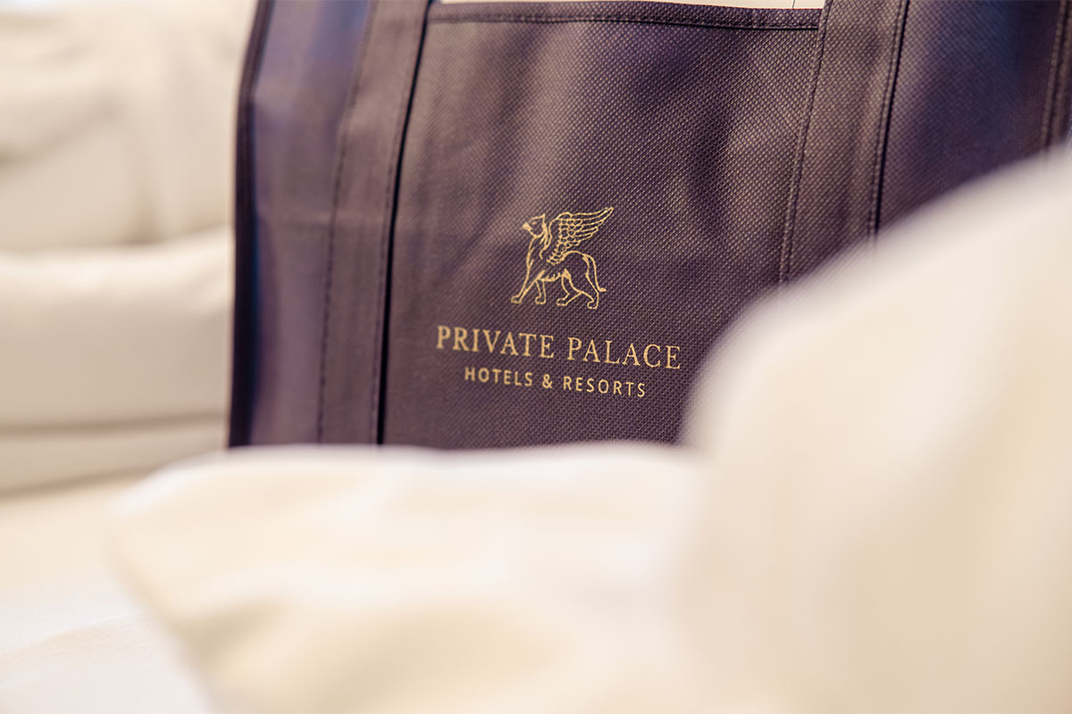 High-quality fabric bag with Private Palace Hotels & Resorts logo on the bed at Rugard Strandhotel Binz