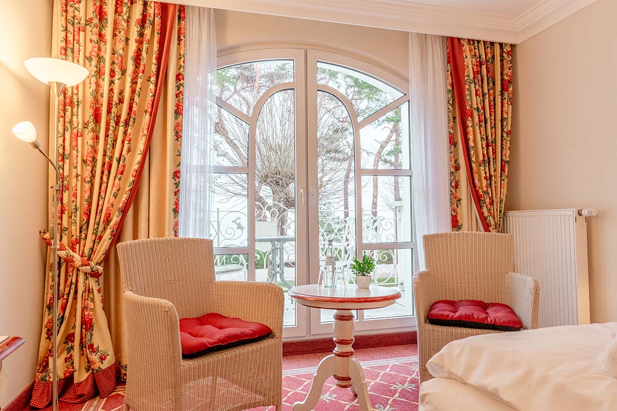 Elegante Sitzecke mit Rattanstühlen, Tisch und Balkonblick auf die Natur im Rugard Thermal Strandhotel