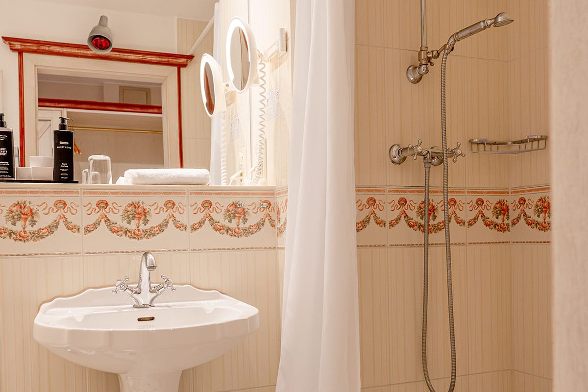 Stilvolles Badezimmer mit Dusche, Spiegel und klassischen Fliesen im Rugard Thermal Strandhotel Binz
