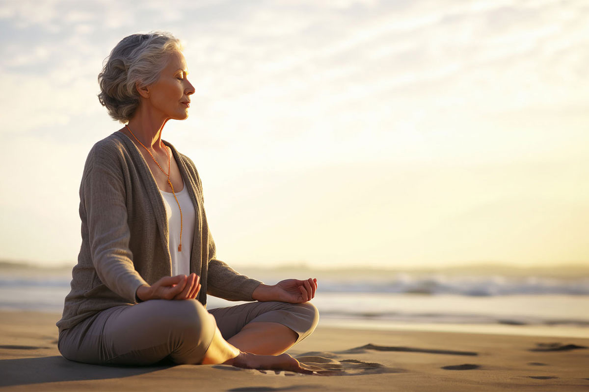 Frau meditiert beim Sonnenuntergang am Ostseestrand auf Rügen beim Meditationsangebot des Rugard Thermal Strandhotels.