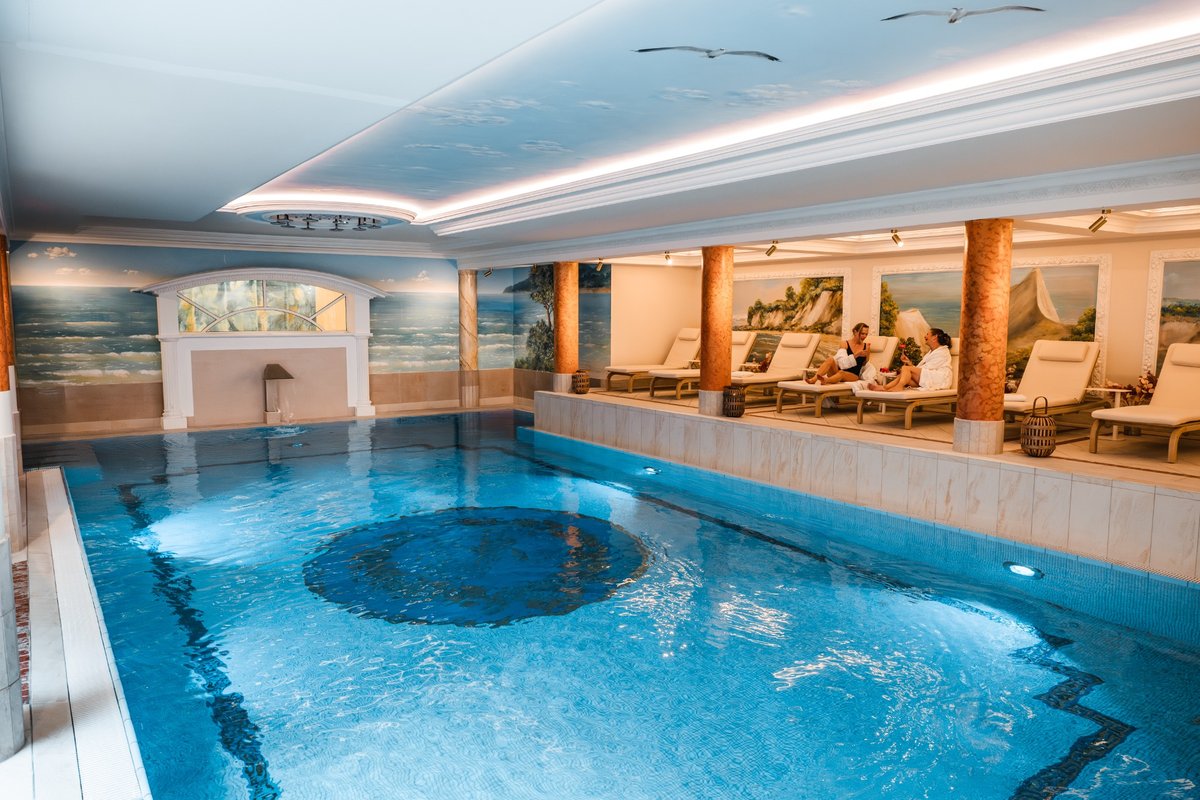 Guests relax in the blue pool with white-copper-coloured columns in the background.