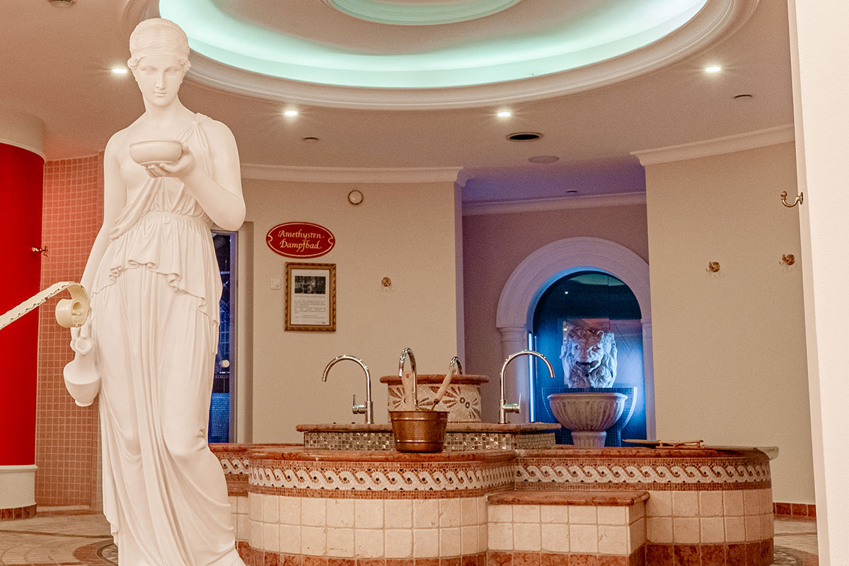 Blick auf die Eisbrunnen-Anlage mit Löwenkopf und Statue im Wellnessbereich des Rugard Thermal Strandhotels.