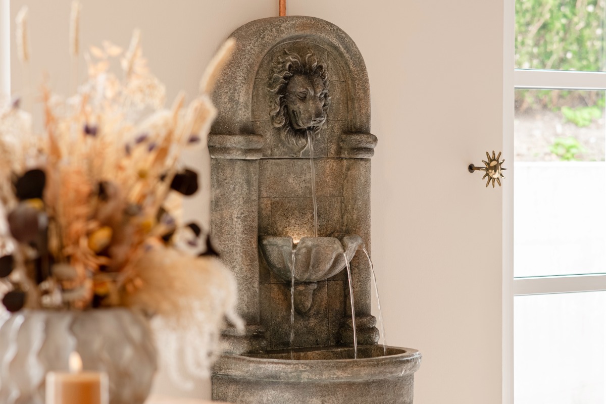 Wasser fließt aus Löwenkopfbrunnen über mehrere Ebenen im Wellnessbereich des Rugard Thermal Strandhotels.