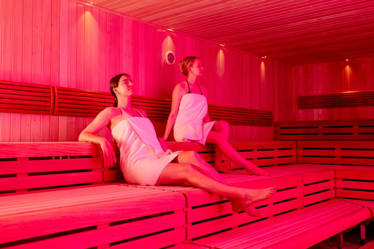Zwei Frauen sitzen in der rot beleuchteten finnischen Sauna des Rugard Thermal Strandhotels.