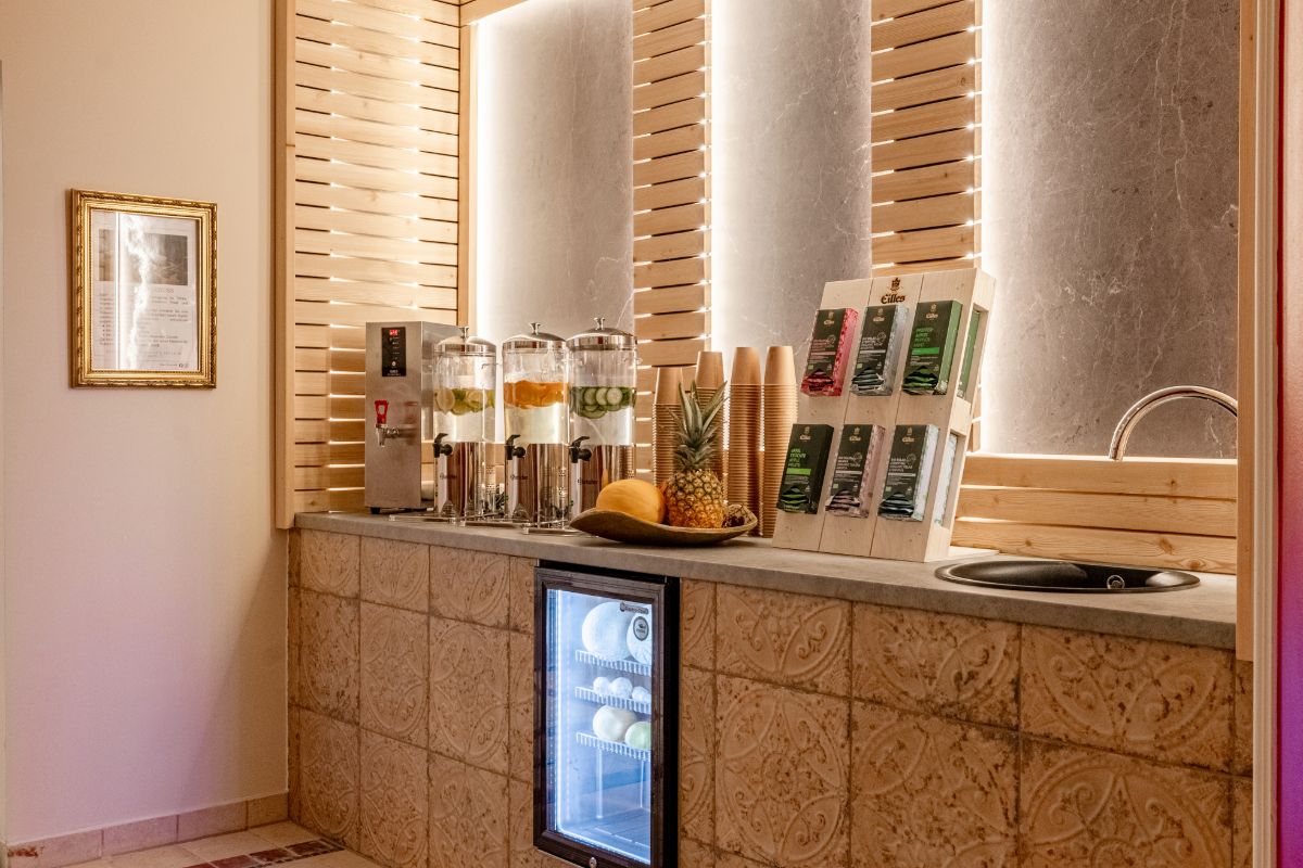 Wasserstation mit Glasdispensern, frischen Früchten und Trinkbechern im Spa-Bereich des Rugard Thermal Hotels.