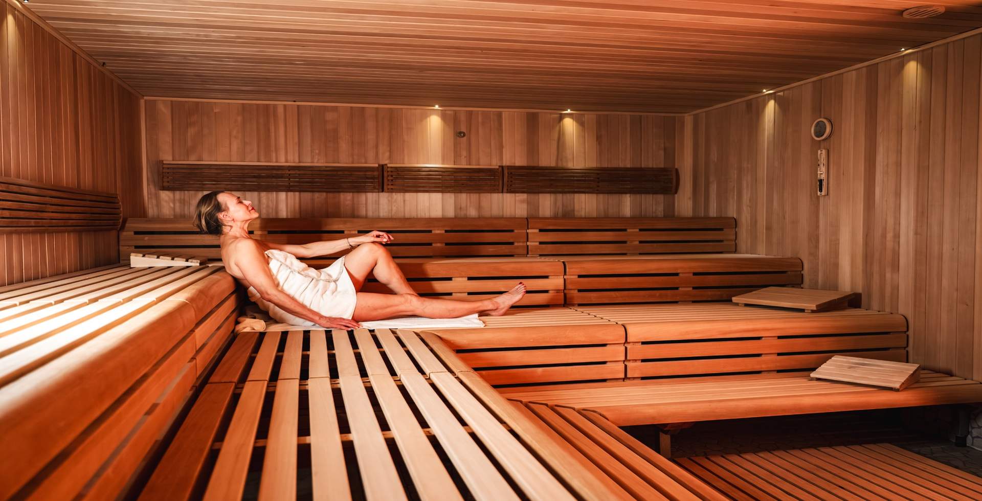 Roman-inspired sauna with wooden benches, natural stone stove and warm ighting in the spa at the Rugard Thermal Strandhotel on Rügen.