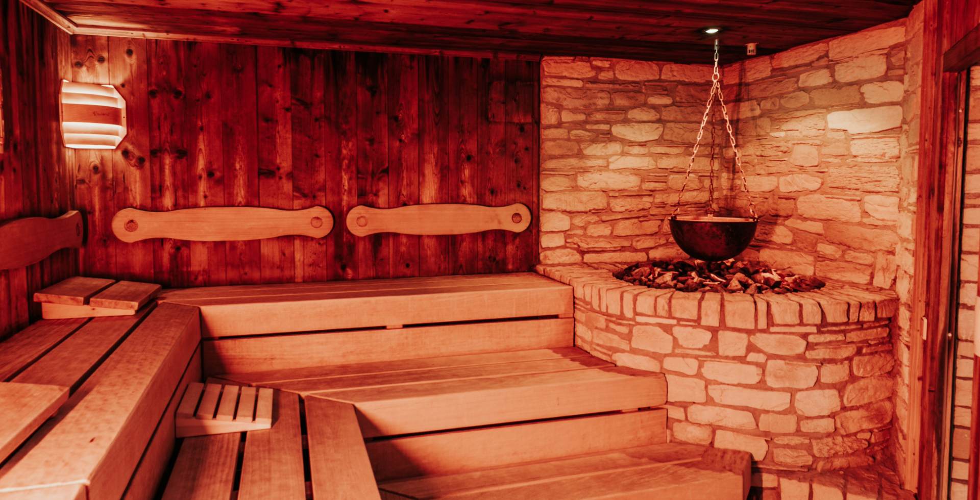 Römisch inspirierte Sauna mit Holzbänken, Natursteinofen und gedämpftem Licht im Spa des Rugard Thermal Strandhotels auf Rügen.