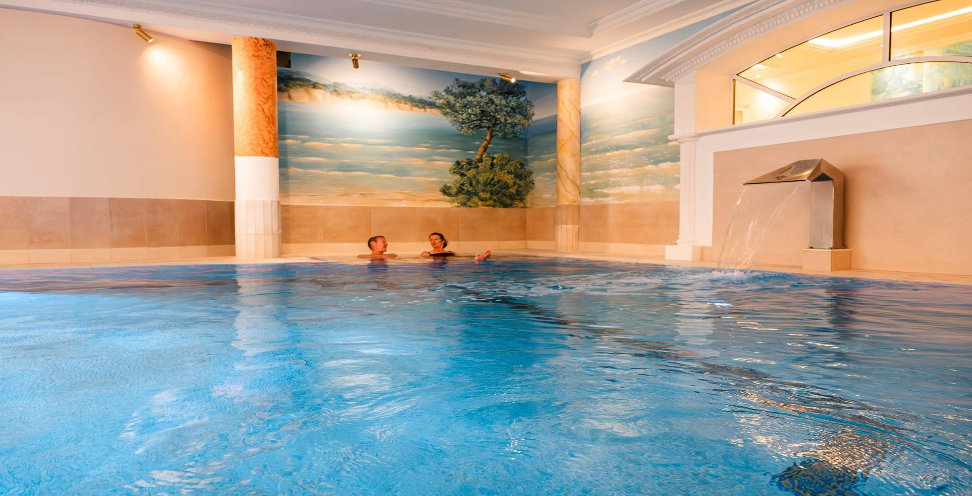 Woman relaxing in the wellness pool with waterfall at the Rugard Thermal Strandhotel spa in Binz.