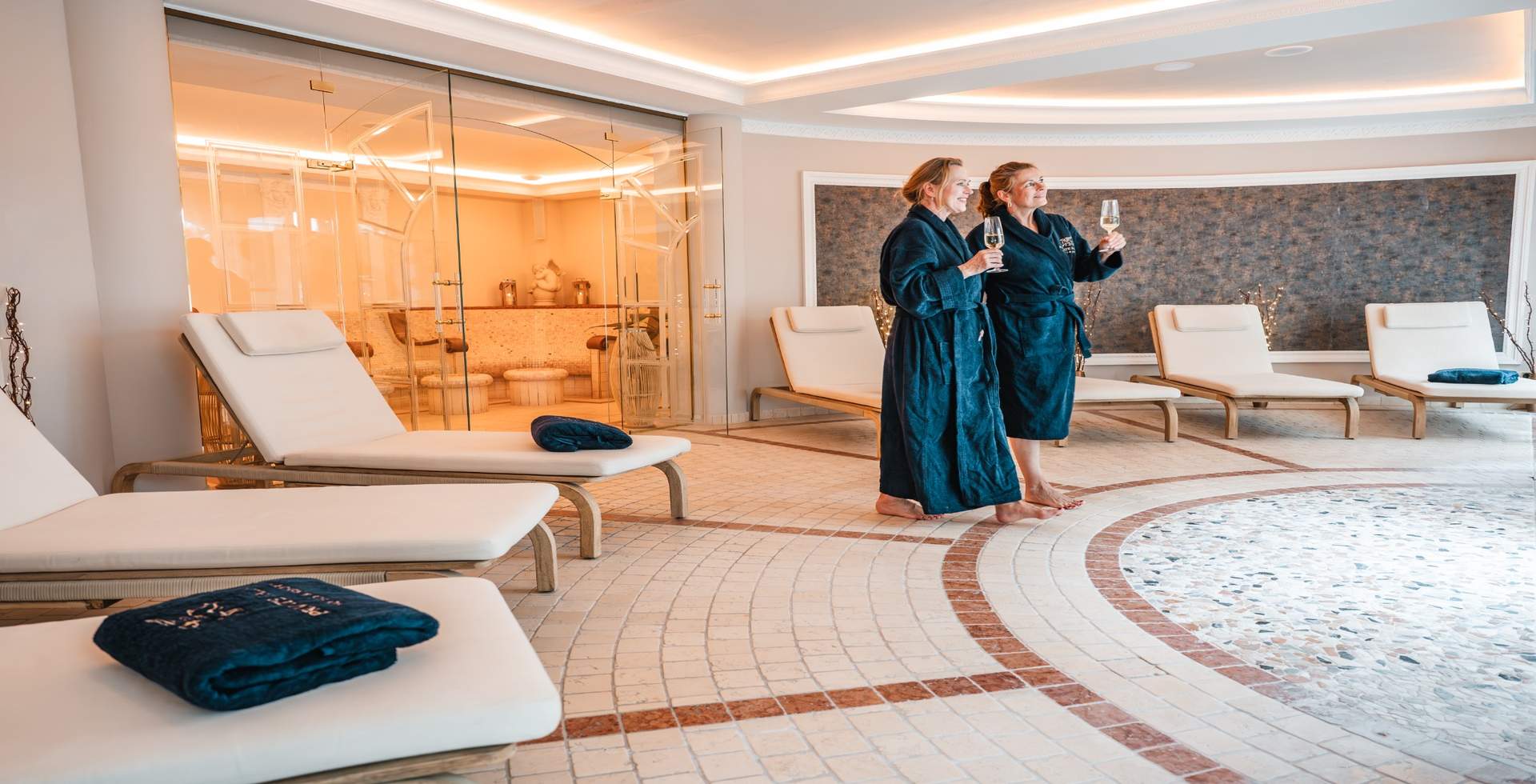 Two guests relaxing on heated loungers in the wellness area of Rugard Thermal Strandhotel.
